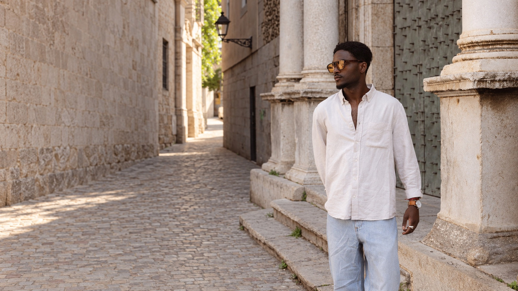 Un hombre con gafas de sol PALADIO junto a una arquitectura clásica de piedra